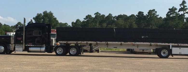 side view of a black Blann Tractor flat bed truck